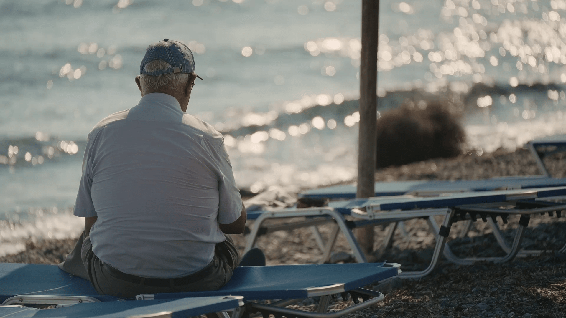 vlcsnap-2024-04-28-01h36m10s930 Αn old man sitting on a beach chair and gazing at the sea. Film still from the documentary "A couple of years".
