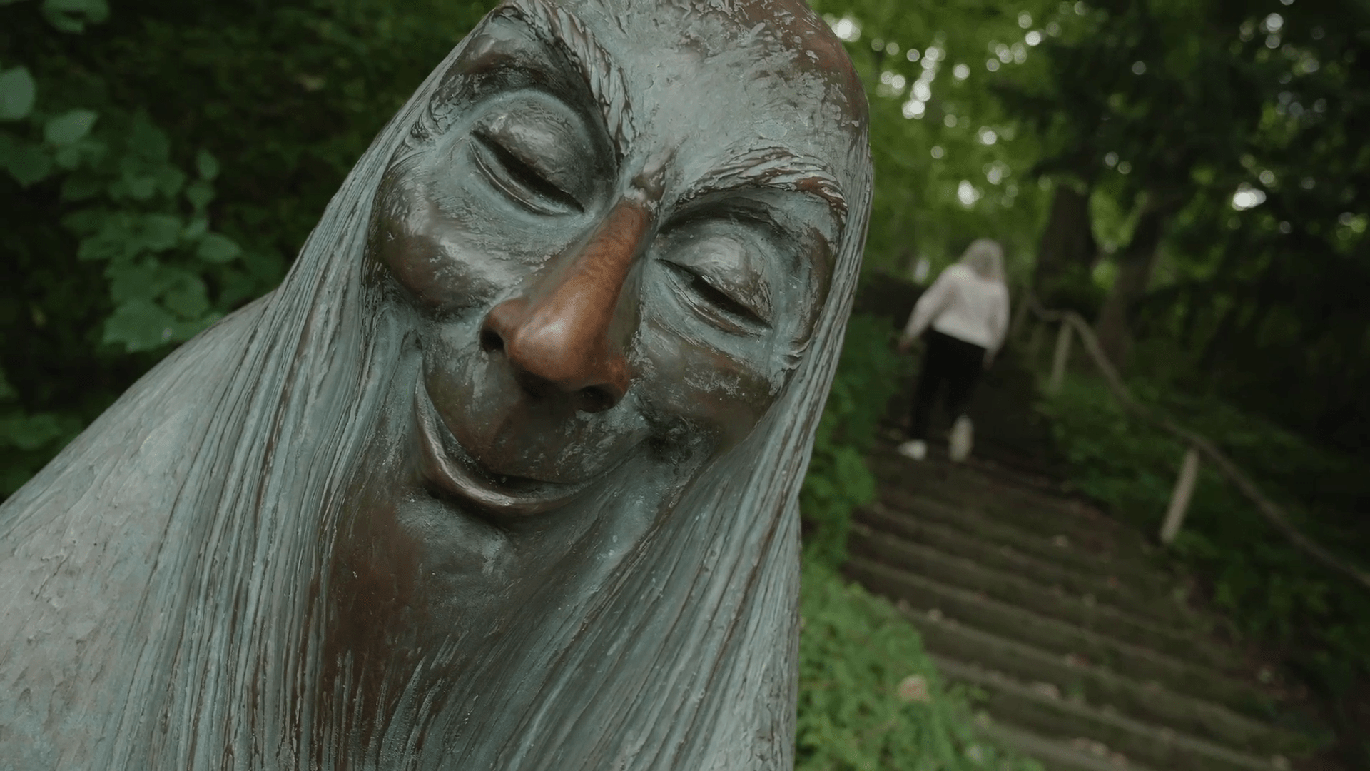 vlcsnap-2024-04-28-01h40m19s658 A woman walking through the gardens of Ludwigsburg. DIagonal shot with a statue at the forefront. Film still from the documentary "A couple of years".